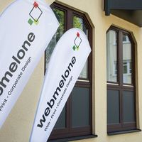 Außenansicht der webmelone von Osten - Beachflags mit webmelone Logo und Fensterfront